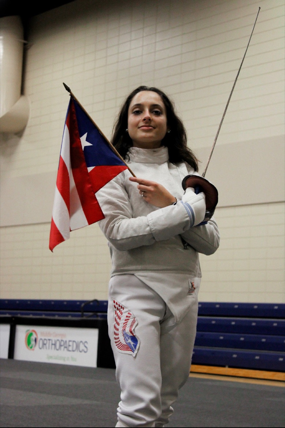 Fencer holding the Puerto Rico flag and a foil