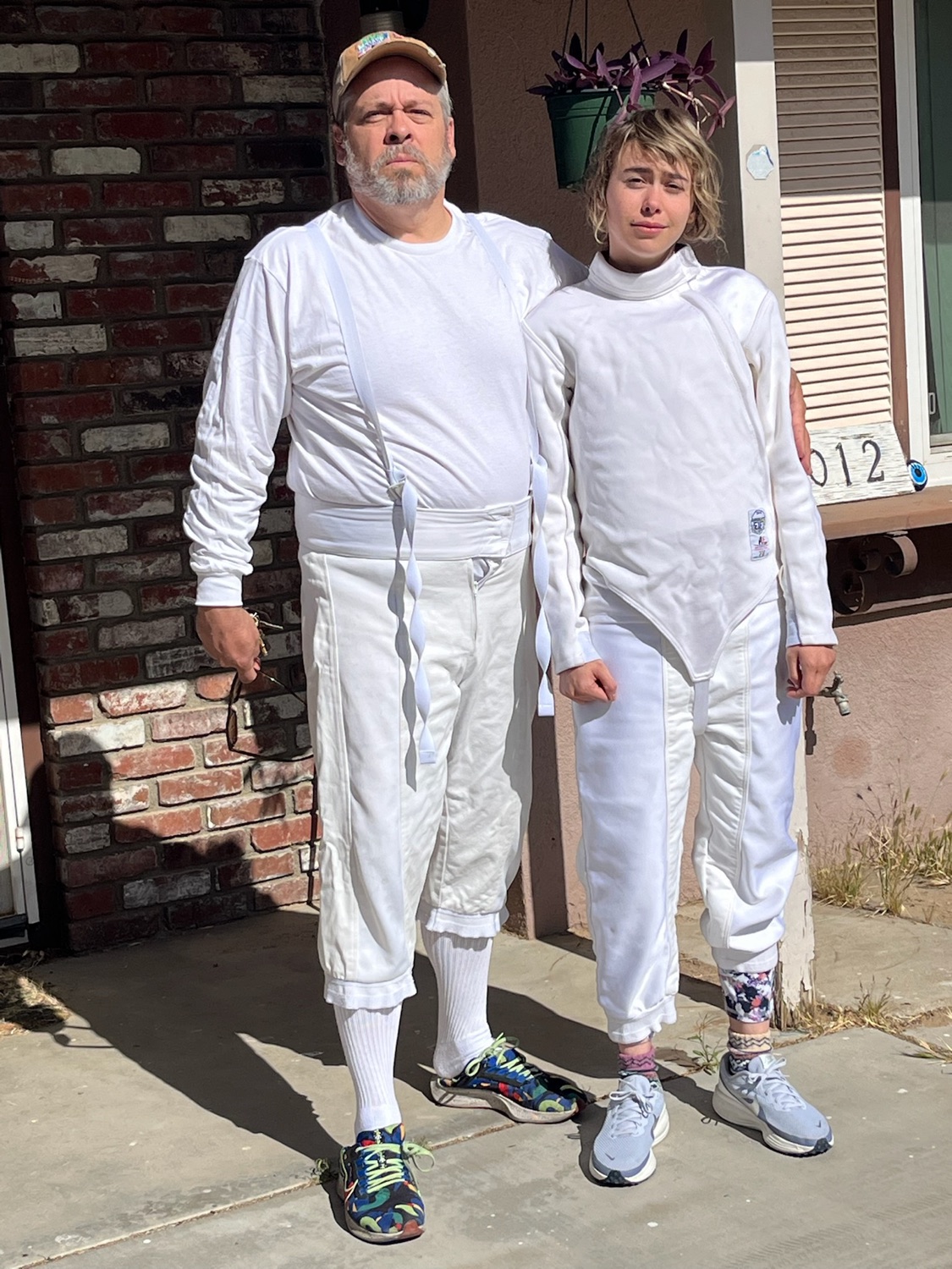 Two fencers standing together in full white fencing uniforms