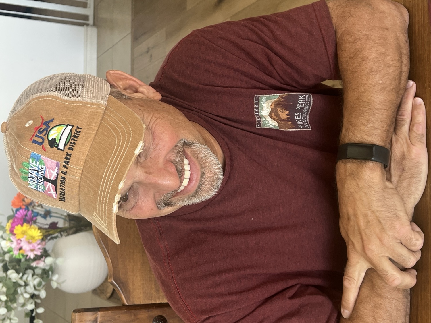 Coach smiling while wearing a tan distressed Mojave Fencing trucker cap