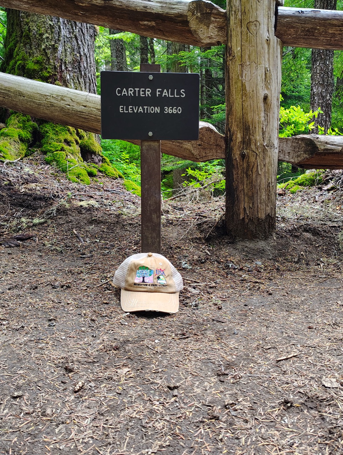 Tan Mojave Fencing trucker cap resting at the Carter Falls trail sign